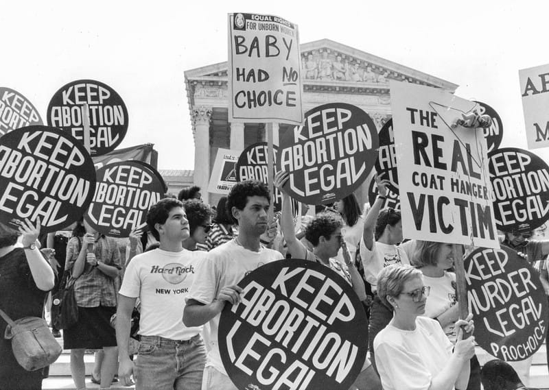 Black-and-white photos of women and men holding signs reading "Keep abortion legal," "Baby had NO choice," and other things.