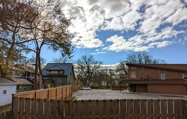 A photo of the church parking lot over the fence behind our house, and the houses next to it.